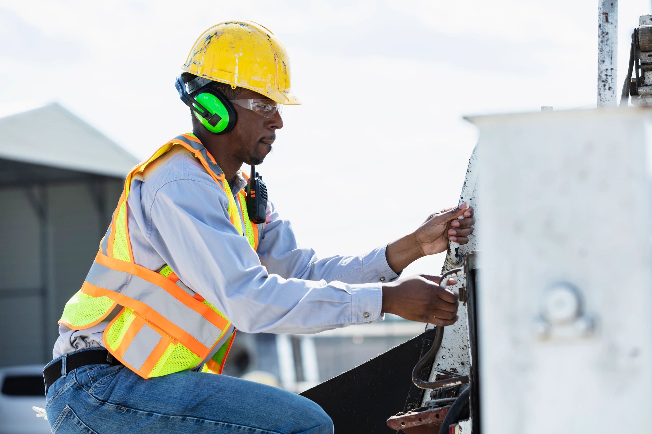 Technician in safety gear working on equipment at a job site