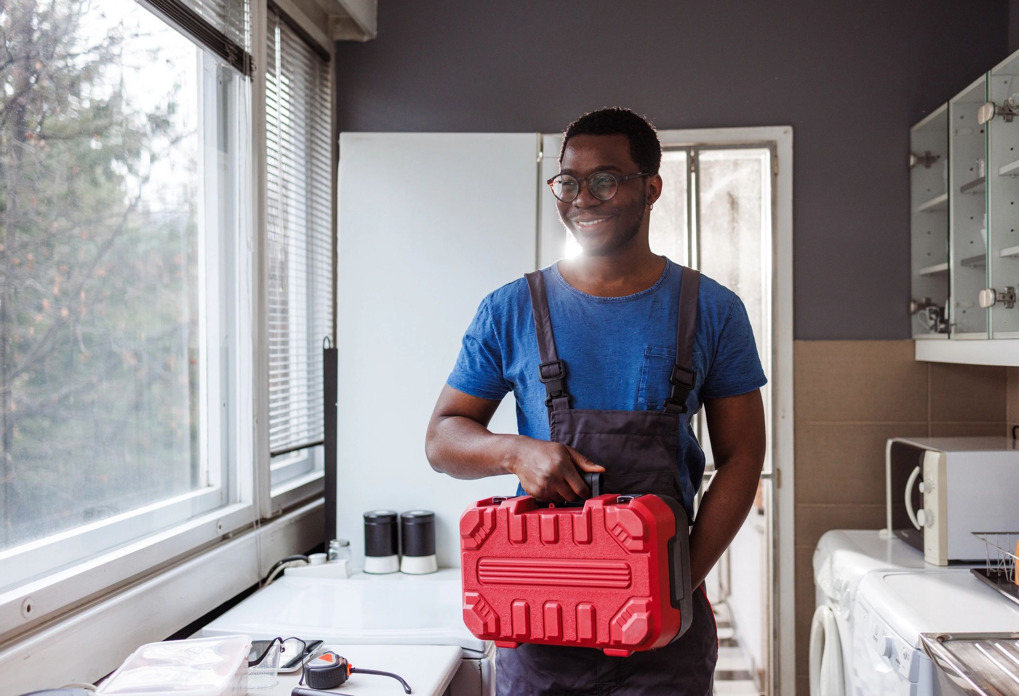 Technician holding a toolbox in a home setting